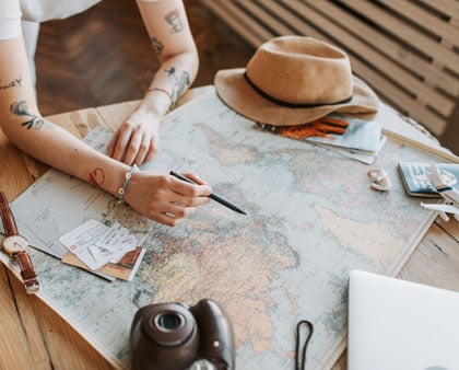 femeie marcheaza urmatoarea destinatie de vacanta pe o harta