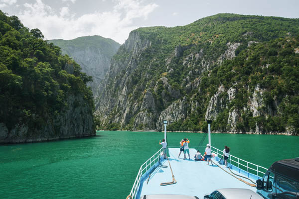 oameni pe barca pe lacul komani din albania
